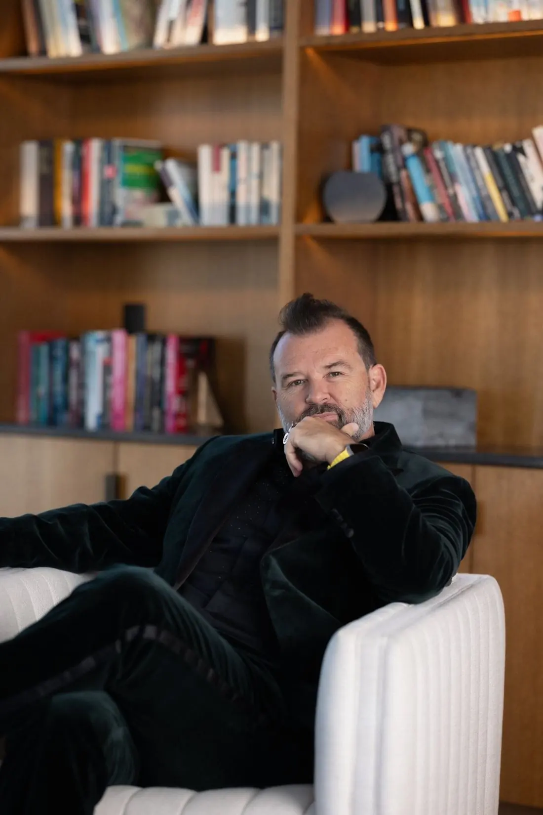 Philippe Cesson seated in front of a bookshelf, chin on his fist